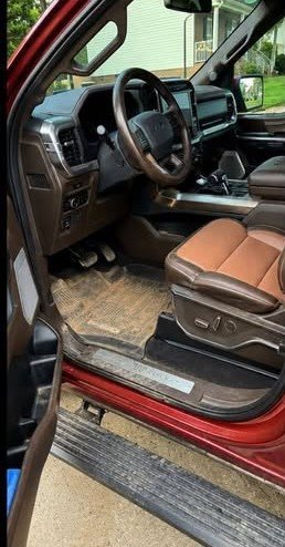 Before: muddy Ford F-150 King Ranch driver floor, footwell and door sill caked with dried mud before a Gleam Team mobile interior detail in Charlotte NC
